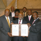 Lerone Bennett Jr. holds a resolution in his honor from the State Senate in his home state of Mississippi in 2007. He is flanked by State Sens. David Jordan (left) and John Horhn, with Rep. Omeria Scott and Sen. Willie Simmons (center) and Sen. Hillman Frazier and Rep. Willie Perkins in the rear. (Credit: Mississippi State Senate)